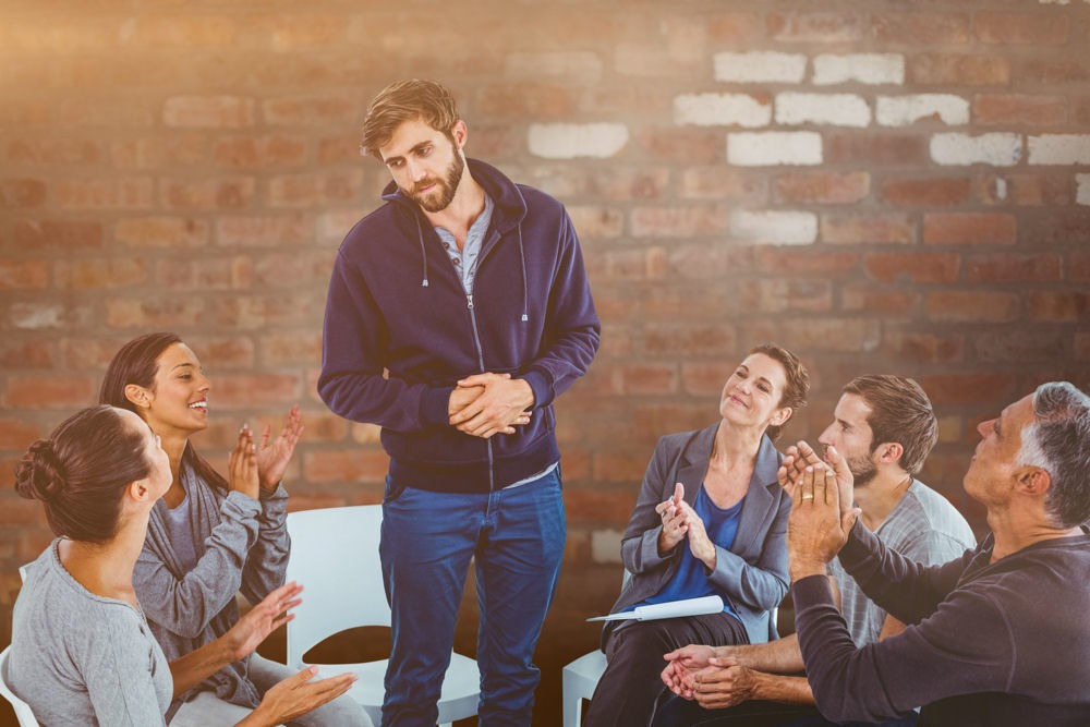 man standing and sharing in group therapy